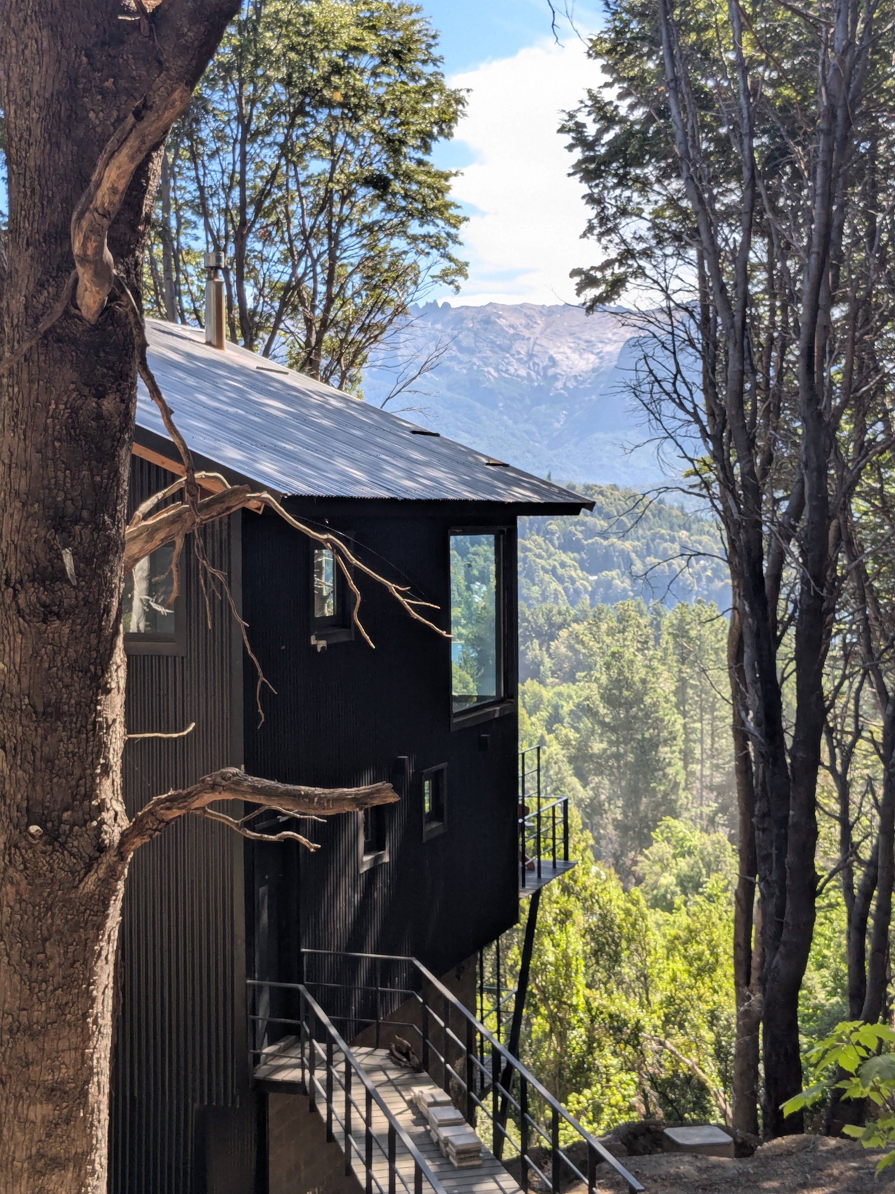 Exterior — black tower, corrugated steel, Cerro López behind