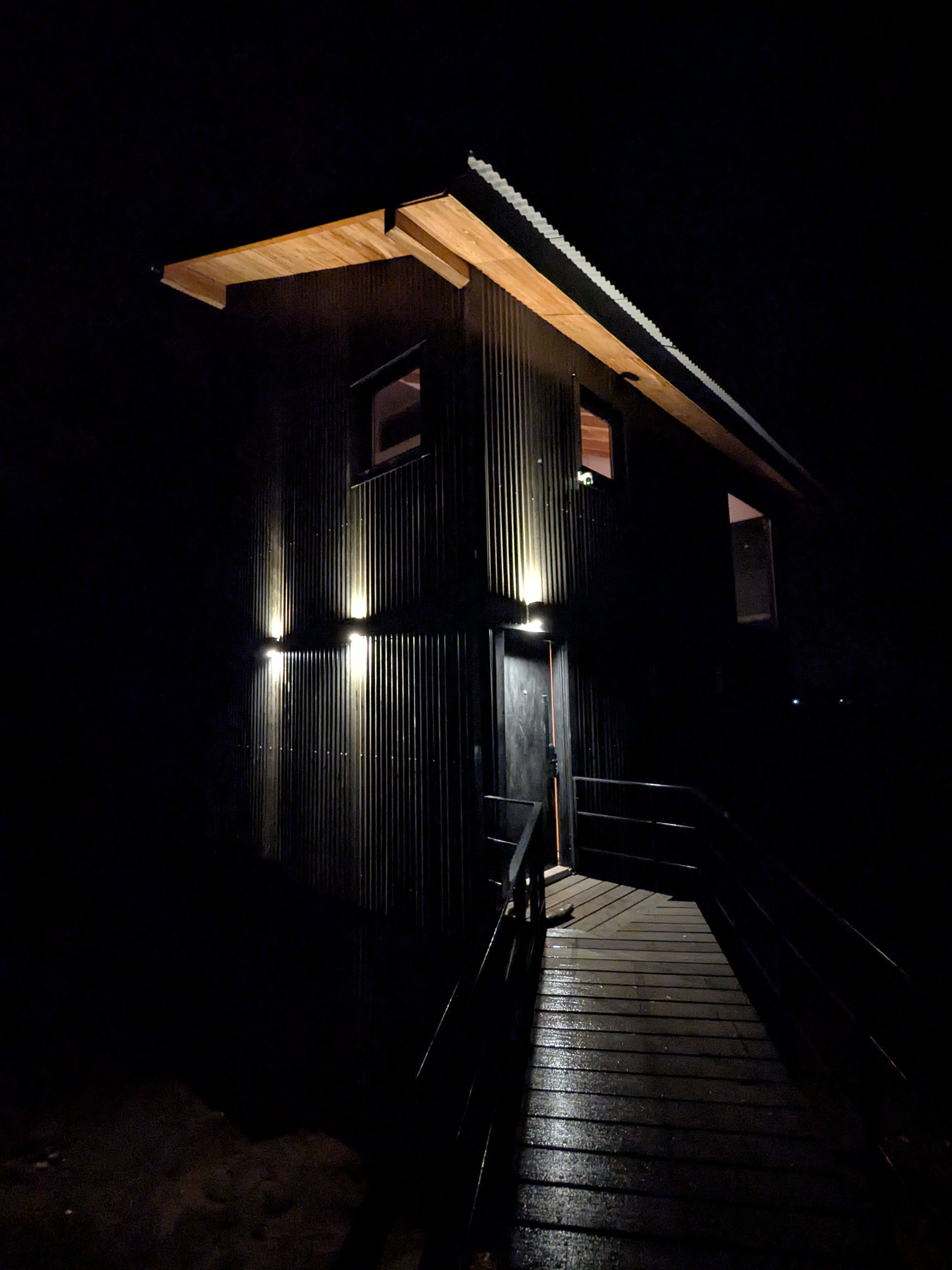 Posta Bariloche at night — black tower lit against the dark forest